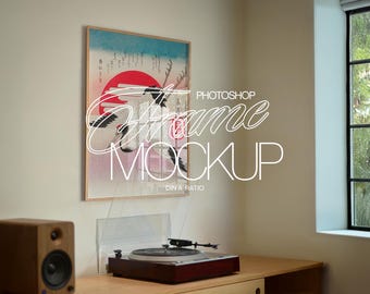 May include: A framed print featuring a Japanese-style illustration of cranes, a red sun, and text. The frame is light-colored wood. Below, a turntable with a clear cover sits on a wooden cabinet, next to a wooden speaker.