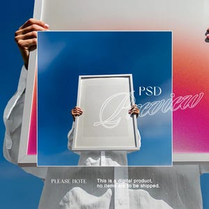 May include: A person holding a white framed artwork against a blue sky. The artwork has a white border and interior. The background has a pink, orange, and white gradient. The text "PSD Preview" is overlaid on the artwork. The text "PLEASE NOTE" is also visible.