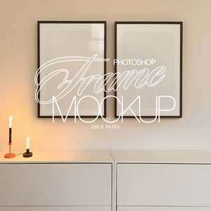 May include: Two black framed pictures with white mats hanging on a light beige wall above a white dresser with two drawers. Two black candle holders with lit candles are on the dresser.