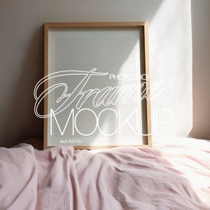 Op de afbeelding: Een houten fotolijst met een witte passe-partout en een 4x5 verhouding. De lijst ligt op een roze bedsprei met zonlicht dat door een raam schijnt.