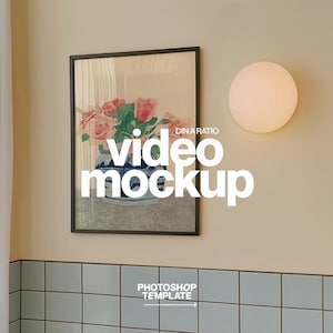 Puede incluir: Una obra de arte enmarcada con un bodegón floral con rosas rosas en un jarrón azul y blanco. La imagen está montada en una pared beige, con una lámpara redonda y una sección de pared alicatada. El texto "video mockup" está superpuesto.