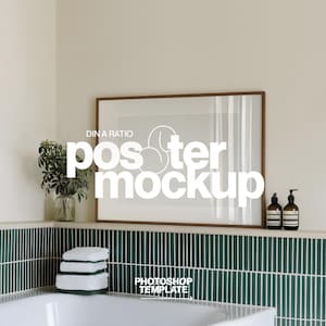 May include: A bathroom scene featuring a large framed poster mockup with the text "poster mockup". The frame is brown, and the wall is a neutral color. Below, a green tiled wall and a white bathtub are visible. A small plant and two brown bottles are on the shelf.