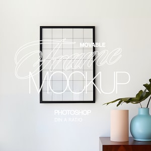 以下が含まれることがあります： 「MOVABLE Frame MOCKUP」と「PHOTOSHOP DIN A RATIO」の文字が入った黒いフレームのグリッドモックアップ。水色の花瓶と桃色の円柱が木製の表面に置かれています。