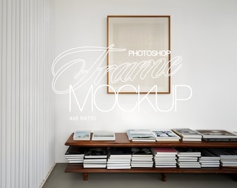 May include: A brown wooden frame with a white mount and a blank white canvas inside. The frame is hanging on a white wall above a wooden shelf with books stacked on it. The text "PHOTOSHOP FRAME MOCKUP 4x5 RATIO" is written in white on the wall.