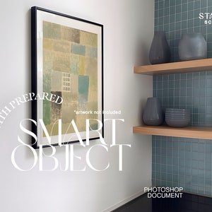 May include: A framed abstract painting with a geometric pattern in shades of green, blue, and brown hangs on a white wall. The painting is in a black frame and is positioned above a shelf with two gray vases and a stack of gray plates. The shelf is made of wood and is mounted on a wall with blue tile.