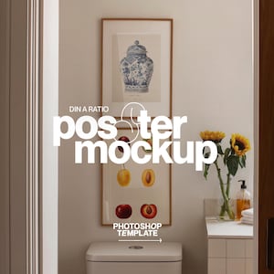 May include: A bathroom interior with two framed art prints. The top print shows a blue and white jar, the bottom print has fruit illustrations. The text "DIN A RATIO" and "poster mockup" are visible. A vase of sunflowers sits on a white countertop, with a toilet below.