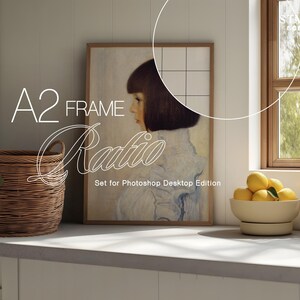 May include: A framed artwork featuring a portrait of a woman with short dark hair and a light-colored dress. The artwork is displayed on a white wall next to a window. A woven basket and a bowl of lemons are in the foreground. Text on the image reads "A2 FRAME Ratio".