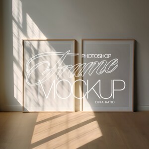 Puede incluir: Dos marcos de fotos de madera con paspartús blancos y fondo blanco. Los marcos están sobre un suelo de madera clara. El texto "Photoshop Frame Mockup DIN A Ratio" está escrito en blanco en el marco de la derecha.