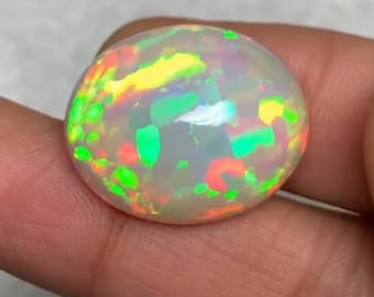 May include: A white opal cabochon with a rainbow of colors, including green, yellow, orange, and red.
