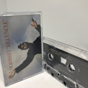 Puede incluir: Una cinta de casete con una caja de plástico transparente. La cinta está etiquetada como "Morrissey "Kill Uncle"" y presenta el texto "Our Frank Asian But Sing Your Live Mute Witness King Leer" y "Produced by Clive Langer and Alan Winstanley".