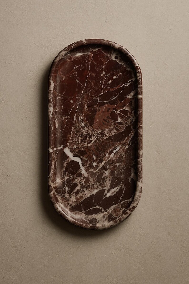 Puede incluir: Una bandeja ovalada de m&aacute;rmol marr&oacute;n. La bandeja tiene un acabado pulido y un patr&oacute;n de m&aacute;rmol natural con vetas blancas. Un art&iacute;culo decorativo para el hogar.