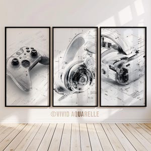 May include: Three framed monochrome prints showcasing gaming equipment. The prints feature a game controller, headphones, and a VR headset, presented in a blueprint design. The artworks are displayed on a white wall above a wooden floor.