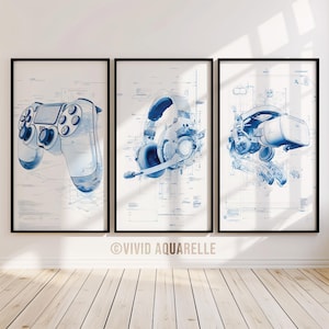 May include: Three framed prints showcasing blue illustrations of gaming equipment: a controller, a headset with a microphone, and a VR headset. The artwork is in a blueprint style, with detailed technical drawings. The prints are displayed on a white wall above a wooden floor.
