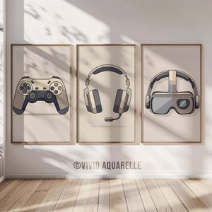 Peut inclure: Trois impressions d'art encadrées représentant des équipements de jeu. Les impressions présentent une manette de jeu beige et grise, un casque avec un microphone et un casque VR. Le fond est de couleur beige clair. Le texte "VIVID AQUARELLE" est en bas.