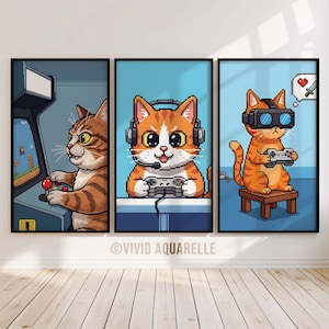 May include: Set of three framed art prints featuring pixelated orange tabby cats. One plays an arcade game, another uses a headset and controller, and the third wears VR glasses and holds a controller. The background is light blue.
