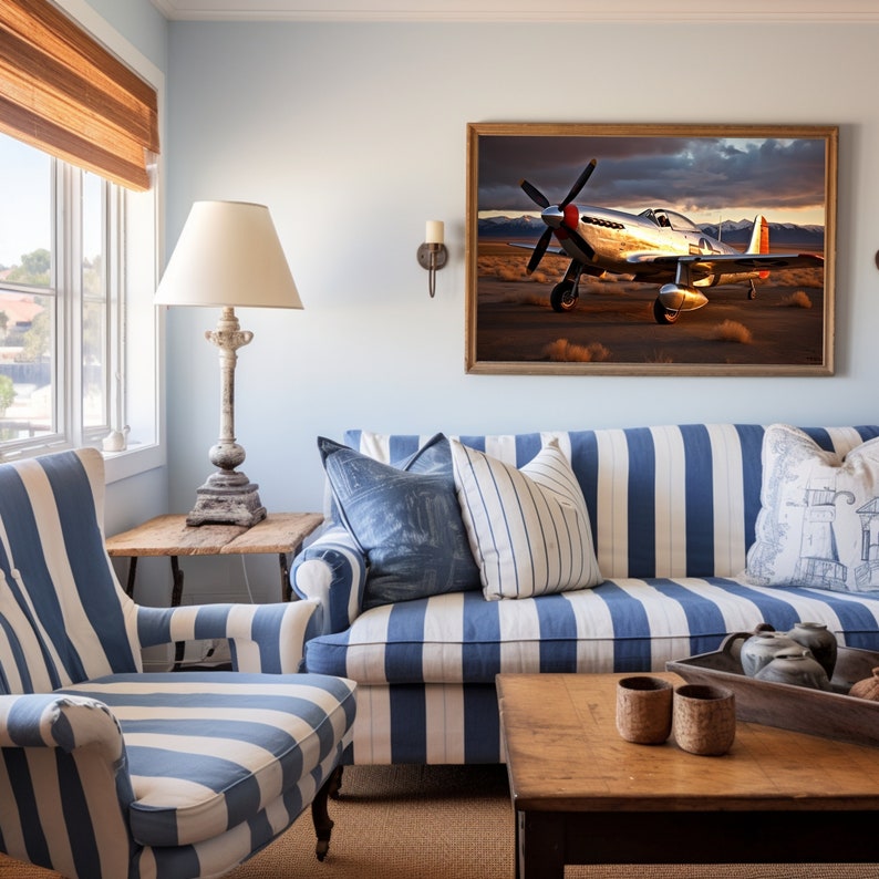 May include: A living room with a blue and white striped sofa, a blue and white striped armchair, and a wooden coffee table. A framed print of a silver airplane hangs on the wall above the sofa.