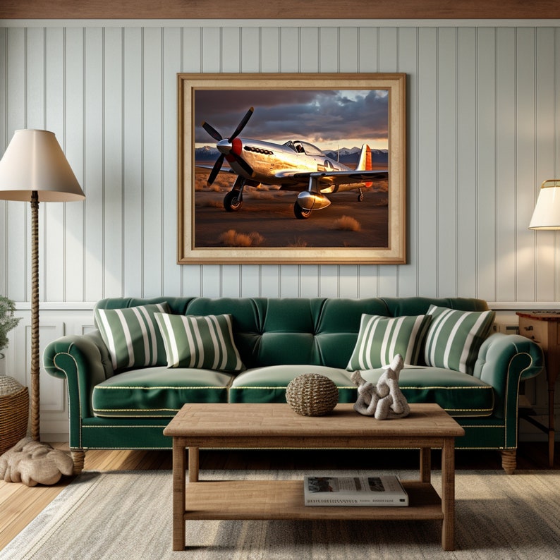 May include: A green velvet sofa with striped pillows sits in front of a framed picture of a silver airplane against a sunset sky. A wooden coffee table with a book and a decorative object sits in front of the sofa.