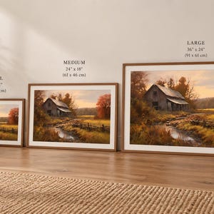 Może przedstawiać: Trzy oprawione wydruki krajobrazowe przedstawiające wiejską stodołę nad strumieniem jesienią, oznaczone jako małe 40 x 30 cm, średnie 61 x 46 cm i duże 91 x 61 cm. Grafika ukazuje ciepłe złote światło, pomarańczowe liście i drewniany płot.