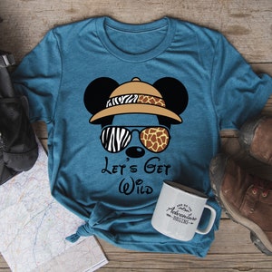 May include: A teal blue t-shirt with a cartoon Mickey Mouse wearing a safari hat and sunglasses. The text "Let's Get Wild" is printed on the shirt.