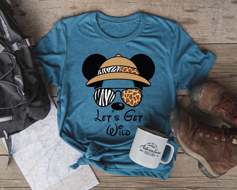 May include: A teal blue t-shirt with a cartoon Mickey Mouse wearing a safari hat and sunglasses. The text "Let's Get Wild" is printed on the shirt.