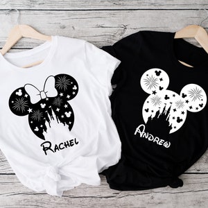 Puede incluir: Dos camisetas blancas con orejas de Mickey Mouse negras y un dise&ntilde;o de castillo. Una camiseta dice "Rachel" y la otra dice "Andrew".