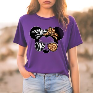 May include: Purple t-shirt with a graphic of a cartoon animal wearing sunglasses. The animal's ears are zebra and giraffe print, and the sunglasses are zebra and giraffe print.