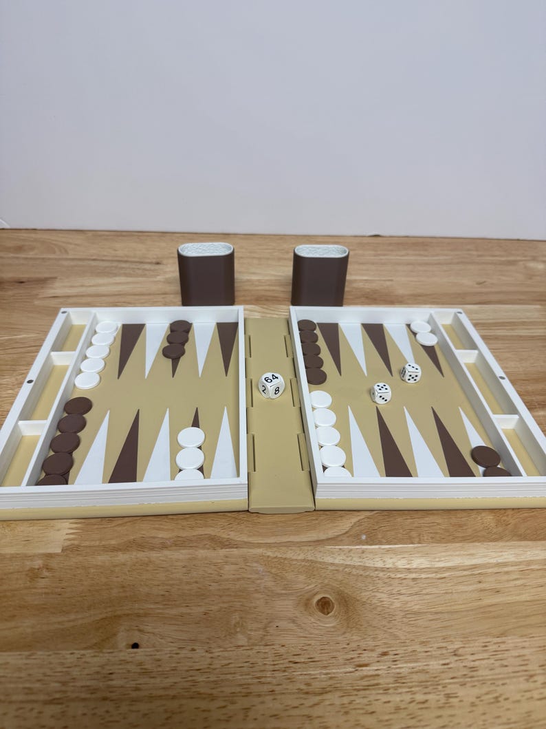 Peut inclure: Un jeu de backgammon avec une surface de jeu beige, des pions blancs et marron, et deux gobelets &agrave; d&eacute;s marron. Les d&eacute;s affichent les chiffres 6, 4, 8, 2 et 3. Le plateau de jeu est ouvert et pr&ecirc;t &agrave; jouer.