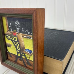 Rustic wood-framed art featuring a chalkboard and desk