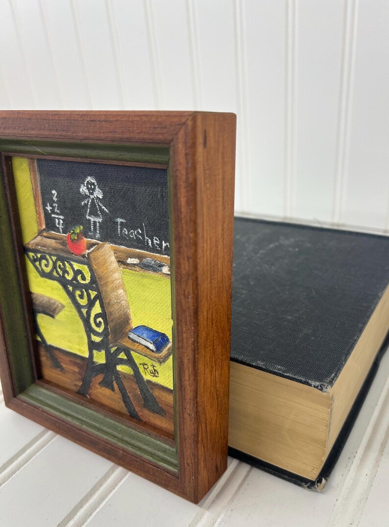 Rustic wood-framed art featuring a chalkboard and desk