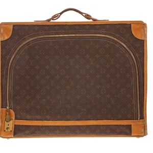 May include: Brown and tan vintage suitcase with a repeating logo pattern. The suitcase has a curved zipper closure, leather trim, and a top handle. The corners are reinforced with tan leather.