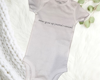 May include: White baby onesie with short sleeves and the text "never grow up (mama's version)" printed on the front.