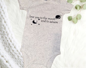 May include: A gray baby onesie with a black graphic that says "love you to the moon and to saturn". The graphic also includes a crescent moon and a planet with a ring.