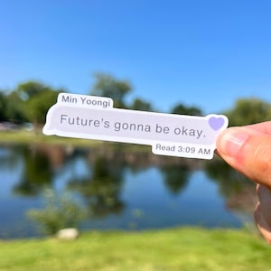 May include: A sticker with a light blue background and white text that reads "Min Yoongi Future's gonna be okay. Read 3:09 AM" with a purple heart icon.