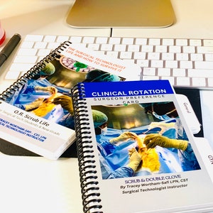 May include: Two spiral-bound books and a card are on a desk. The books have images of surgical procedures and text that reads "O.R. Scrub Life" and "Clinical Rotation Surgeon Preference Card." The card reads "The Surgical Technologist Life and How to Survive It."