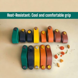 Könnte beinhalten: Sortiment von 12 Leder-Schrankgriffen in verschiedenen Farben, darunter Grün, Blau, Gelb, Orange und Braun. Jeder Griff hat einen goldenen Metallknopf und eine einzigartige Form.