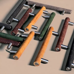 May include: Assortment of leather cabinet pulls in various colors, including brown, green, and tan. The pulls have a stitched design and metal hardware.
