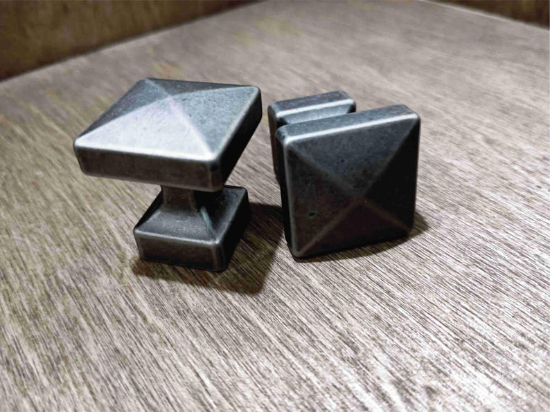 May include: Two silver-toned metal cabinet knobs with a square base and a pyramid-shaped top.
