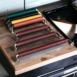 May include: Five leather drawer pulls with brass hardware. The pulls are in various colors, including green, black, yellow, and brown.