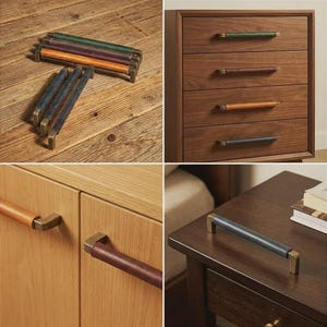 May include: A collection of cabinet pulls featuring cylindrical leather grips in green, brown, tan, and blue, attached to antique brass-toned metal brackets. These hardware pieces are shown installed on wooden drawers and cabinet doors.