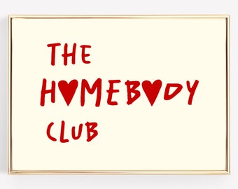 以下が含まれることがあります： 金色の枠で囲まれた白い看板に、赤い文字で「THE HOMEBODY CLUB」と書いてあり、赤いハートが2つあります。