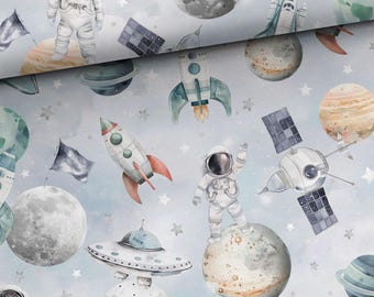 May include: Watercolor illustration of a space-themed pattern. The design features astronauts, rockets, planets, satellites, and a UFO against a light blue background with stars. The artwork has a whimsical, hand-painted style.