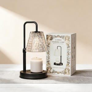 May include: A black candle warmer lamp with a faceted glass shade and a white candle in a ceramic jar. The lamp is on a round base, and a box with the lamp's image and text is next to it.