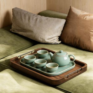 Puede incluir: Una taza de cerámica blanca con un asa negra y el texto "But First, Coffee" en negro, con una fuente de estilo manuscrito. La taza está sobre una superficie blanca.