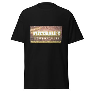 May include: Black t-shirt with a graphic of a brick wall sign that reads "Laugh it up at Fuzzball's Comedy Club. Best of Coruscant award 7 years in a row!"