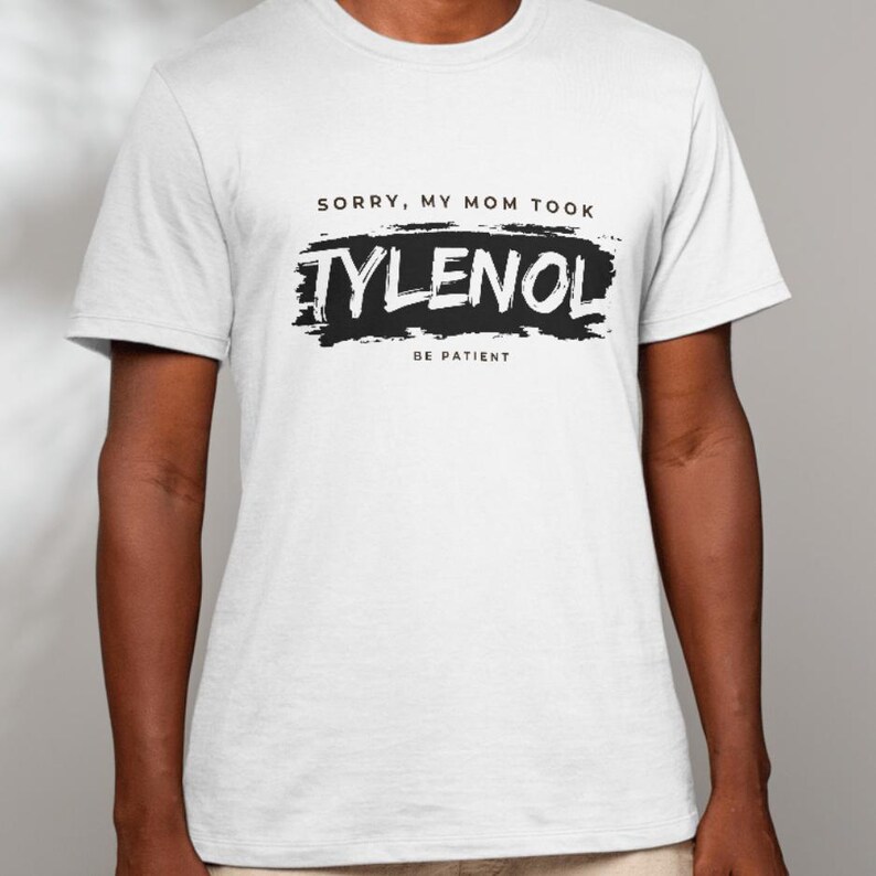 May include: White t-shirt with the text "SORRY, MY MOM TOOK TYLENOL BE PATIENT" in black. The word "TYLENOL" is in a bold, stylized font, and the text is centered on the shirt.