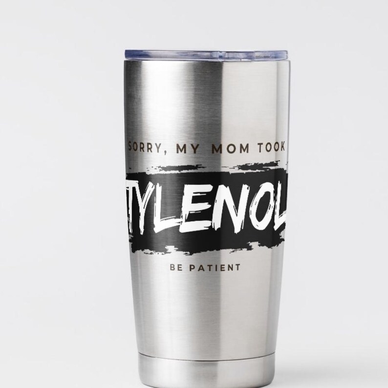 May include: A stainless steel tumbler with a black and white design. The text on the tumbler reads "SORRY, MY MOM TOOK TYLENOL BE PATIENT". The tumbler has a silver lid and a silver body.