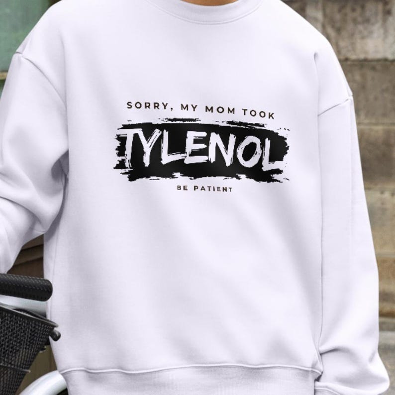May include: White sweatshirt with the text "SORRY, MY MOM TOOK TYLENOL BE PATIENT" in black. The word "TYLENOL" is in a bold, distressed font. The sweatshirt is a casual style.