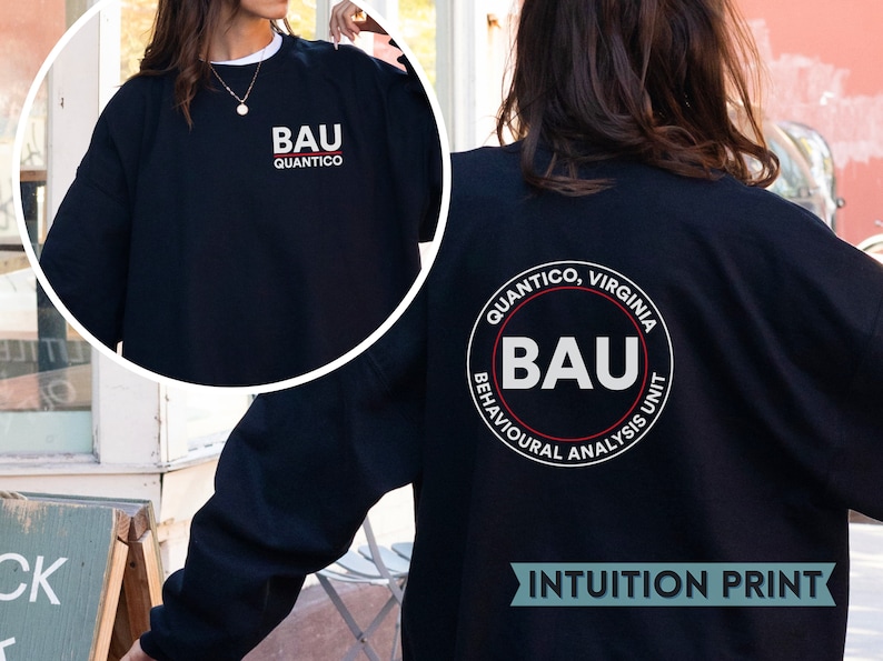 Może przedstawiać: Czarny sweter z białym napisem "BAU Quantico" z przodu i białym kołem z napisem "Quantico, Virginia BAU Behavioral Analysis Unit" z tyłu. Tekst "INTUITION PRINT" jest r&oacute;wnież widoczny w prawym dolnym rogu obrazu.