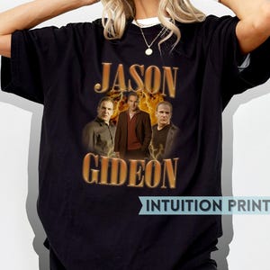 May include: Black t-shirt featuring a graphic print of three men in front of a fiery background. The text "Jason Gideon" is printed in gold lettering.