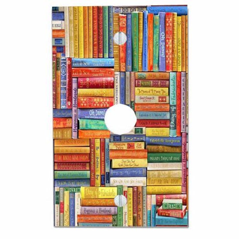 May include: A rectangular light switch cover plate featuring a colourful, dense collage of book spines. The spines display various titles and text including Oh Darn, Let It Sew, and Diary of a Fabricaholic. Three circular cutouts are visible.